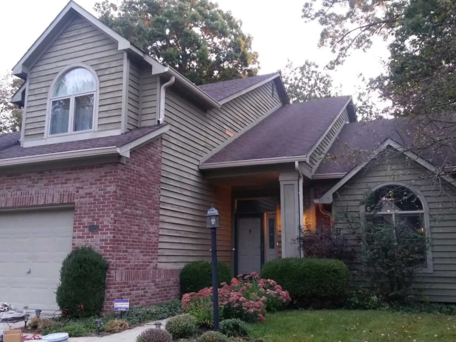 Before: Siding repainted green on a two-story, brick untouched