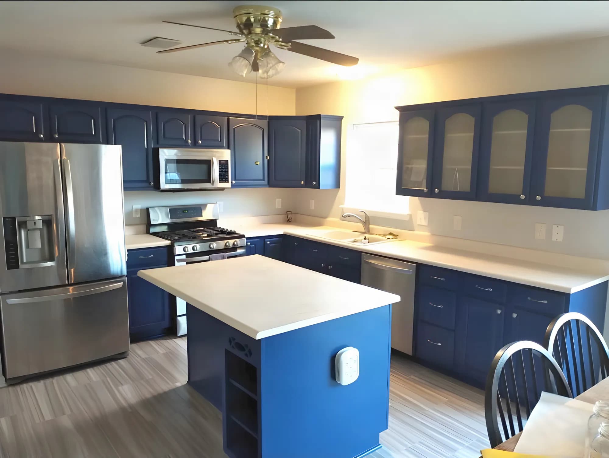 Kitchen cabinets painted navy with a white island top by ALL IN Painting